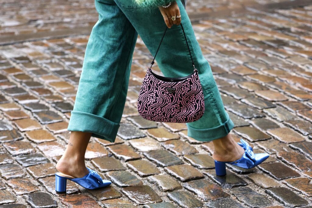 Zena v modrych slapkach, zelenych nohaviciach a so vzorovanou kabelkou