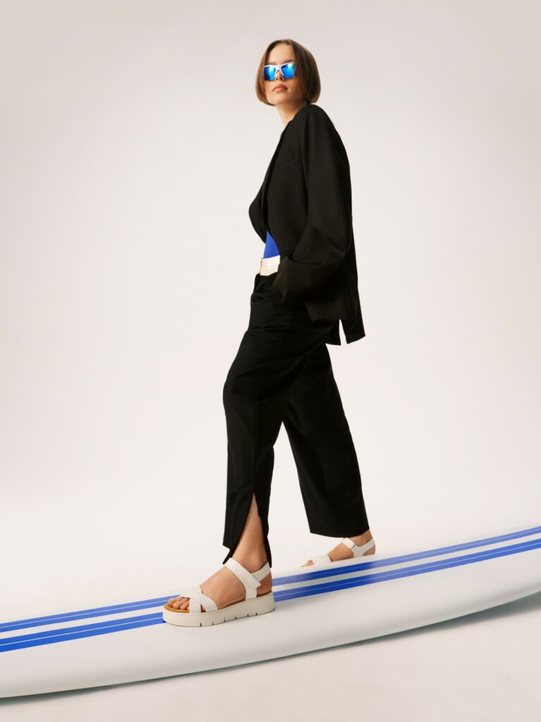 Čierny celkový vzhľad s prvkami modrej farby, biele sandále.
