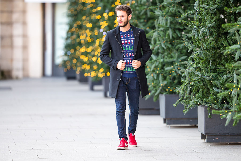 muž kráčajúci po ulici v slávnostnom svetri a červených športových topánkach